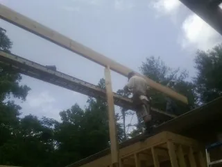 Carpenter setting a ridge beam over a new addition frame — Ice Dam Removal by Roofing Brothers in Pickrell