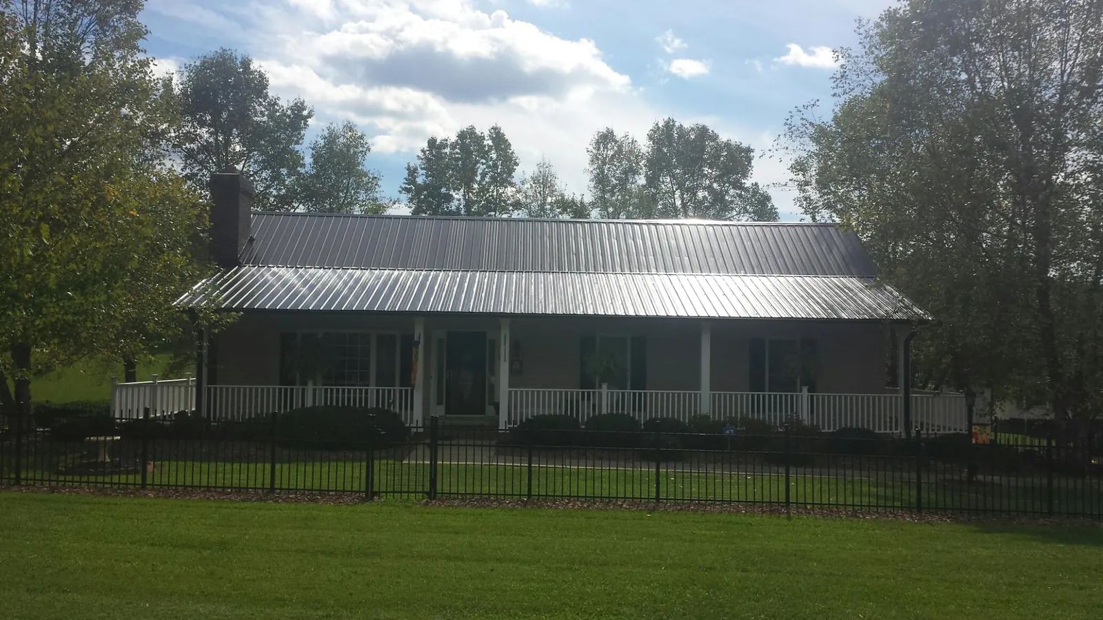 Gray metal roof on a brick ranch with a full width front porch — Gutter Guard Installation work by our crew in Pickrell